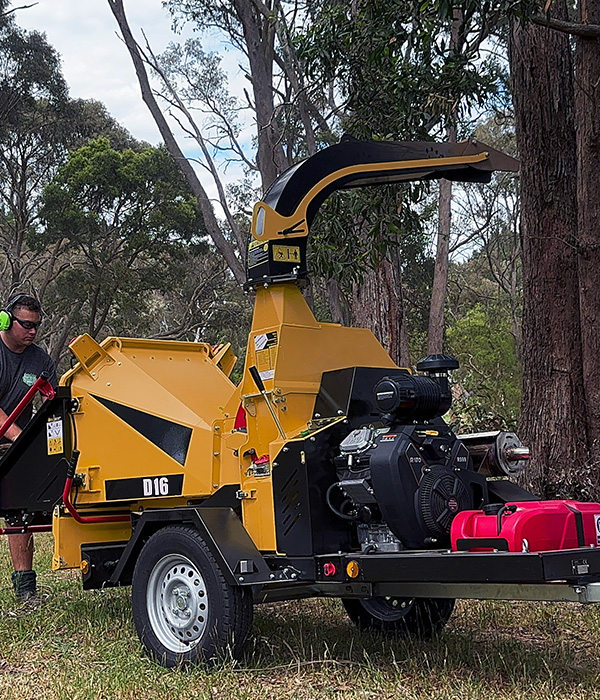 a man standing next to a wood chipper